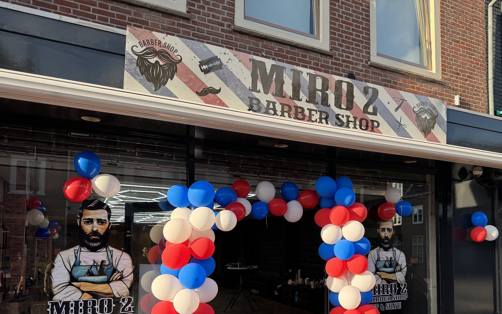 De gevel van Barbershop Miro2 aan de Herenstraat 39 in Rhenen, met het MIRO 2 Barber Shop-bord en een ballonnenboog in rood, wit en blauw bij de opening