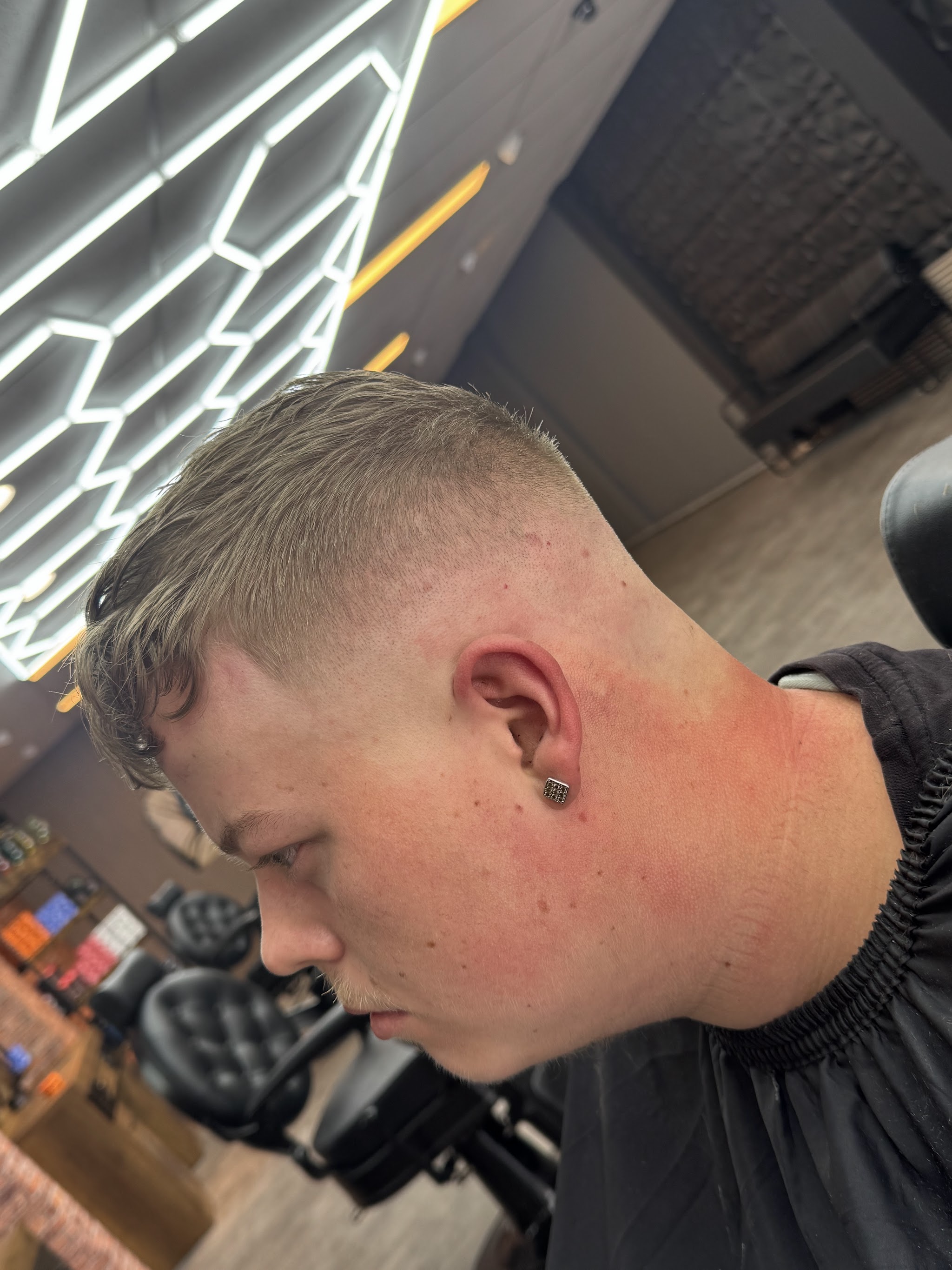Net geknipte fade van bovenaf gezien, klant in een zwarte kapmantel met de zaak op de achtergrond