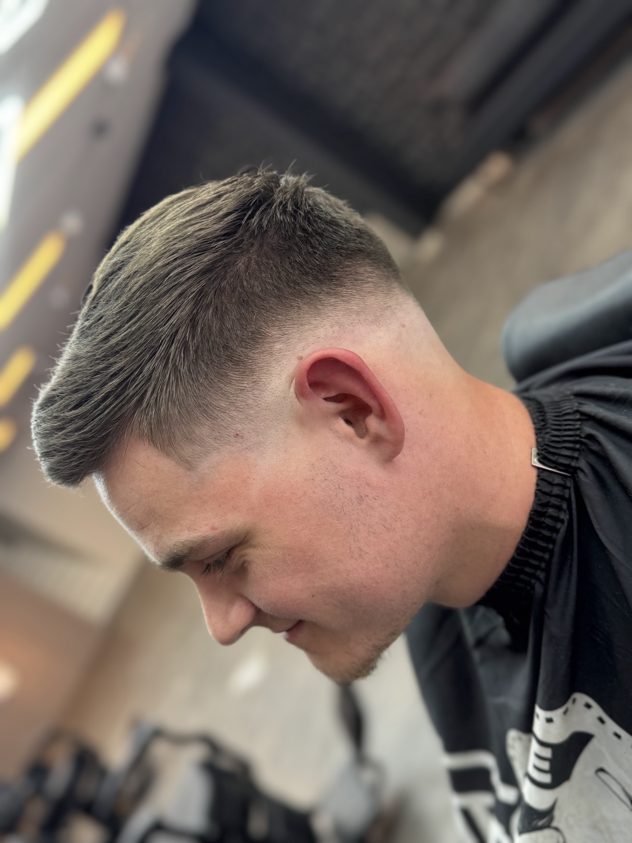 Klant in de stoel met een korte fade aan de zijkant en een opgeföhnde kuif, van opzij gezien